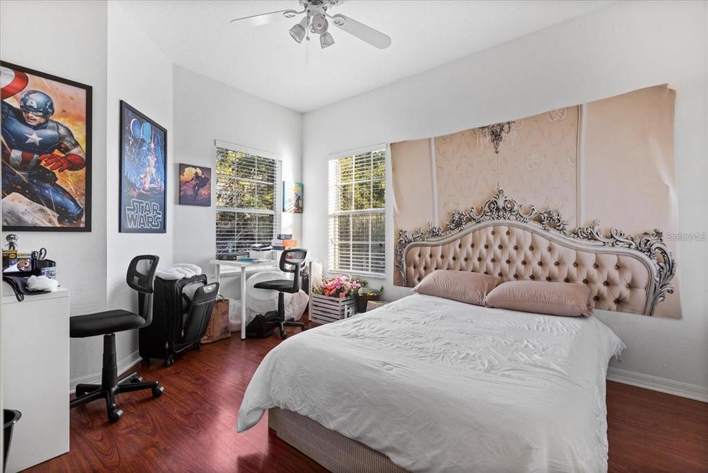 3115 Capri Isle Way Orlando, FL 32835 - Photo 30 of 40 a bedroom with a bed a desk and chair with the wooden floor
