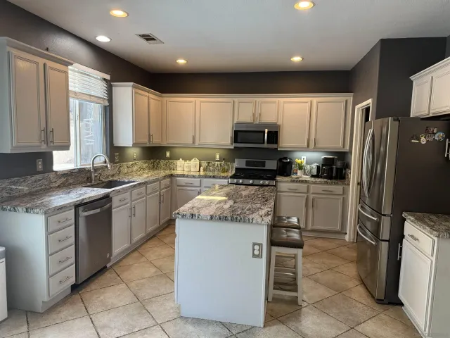 a kitchen with stainless steel appliances granite countertop a refrigerator stove a sink and a microwave