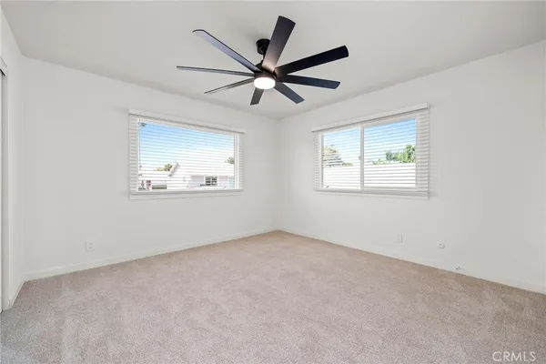 an empty room with wooden floor ceiling fan and windows