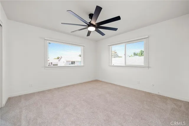 an empty room with wooden floor ceiling fan and windows