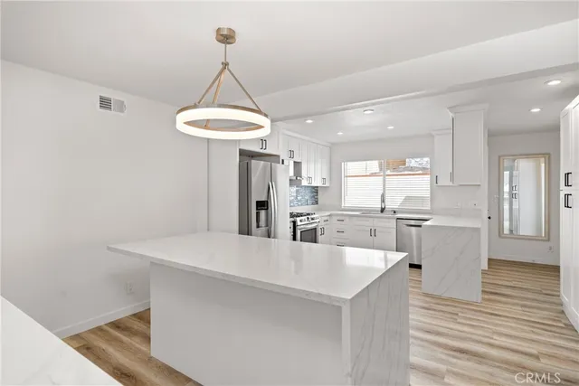 a kitchen with stainless steel appliances a dining table chairs and a refrigerator