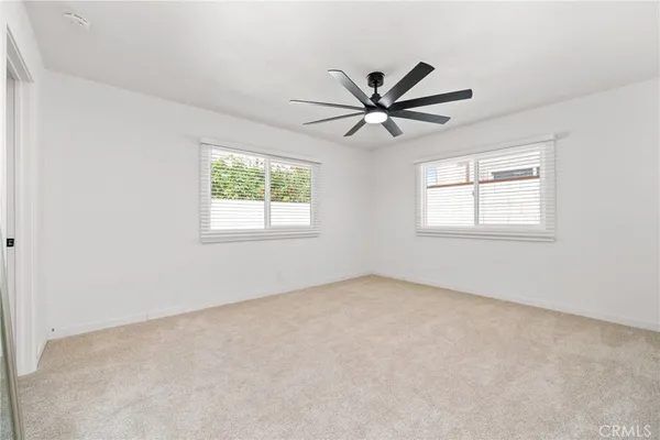 an empty room with windows and fan