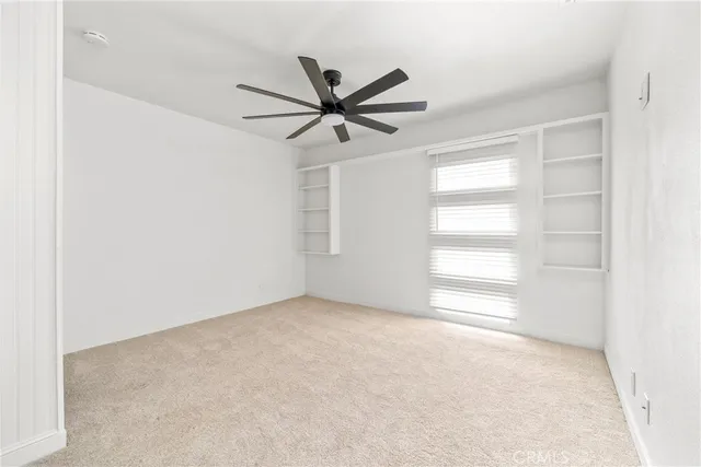 an empty room with windows and fan