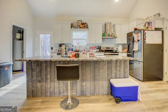 a kitchen with stainless steel appliances kitchen island granite countertop a refrigerator a stove and a wooden cabinets