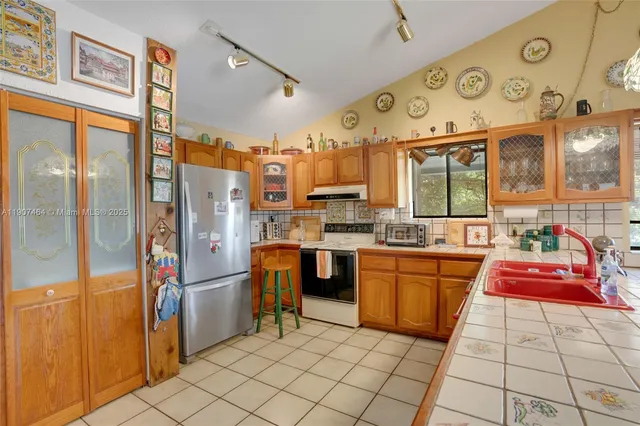 a kitchen with stainless steel appliances granite countertop a refrigerator and a stove top oven