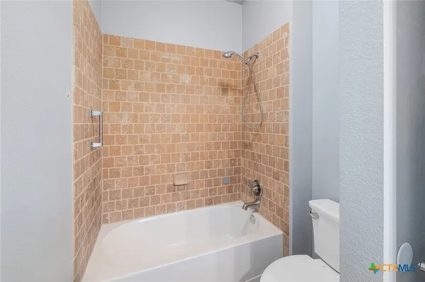 a bathroom with a bathtub shower and toilet