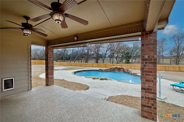 a view of a swimming pool with lawn chairs and a big yard