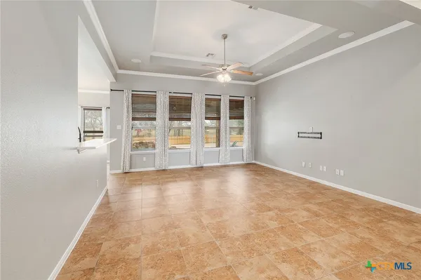 an empty space with chandelier fan and windows