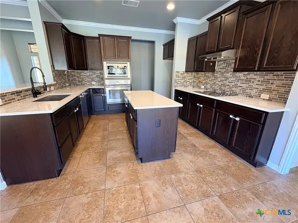 a kitchen with kitchen island granite countertop a sink a counter top space and cabinets
