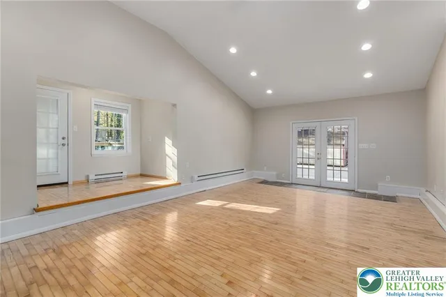 a view of an empty room with window and wooden floor
