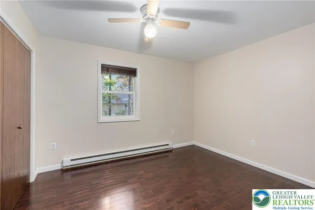 an empty room with wooden floor chandelier fan and windows
