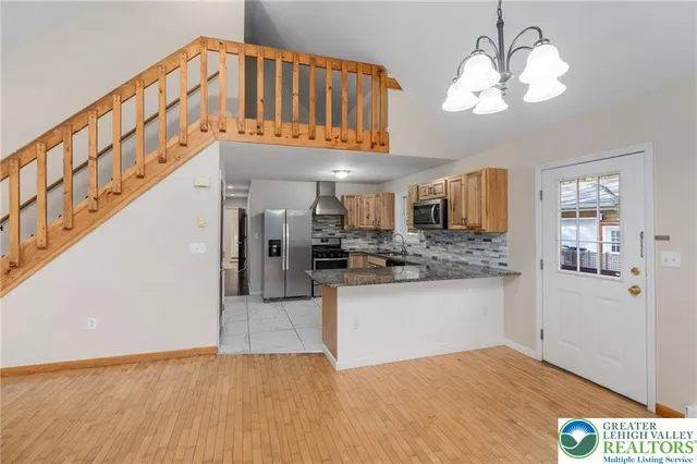 a view of a kitchen with kitchen island wooden floor center island and stainless steel appliances