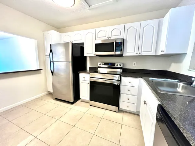 a kitchen with stainless steel appliances granite countertop a refrigerator sink and stove