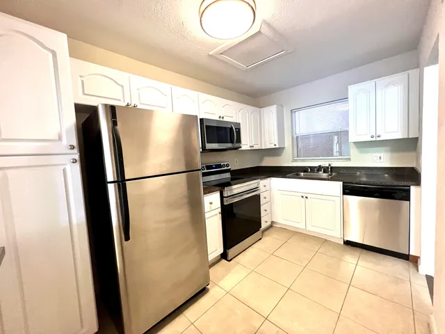 a kitchen with granite countertop a refrigerator stove top oven and sink
