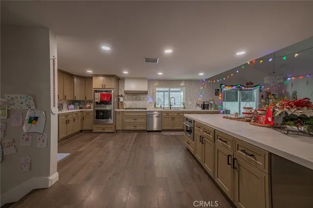 a kitchen with stainless steel appliances kitchen island granite countertop a sink cabinets and wooden floor