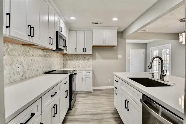 a kitchen with granite countertop white cabinets and wooden floor