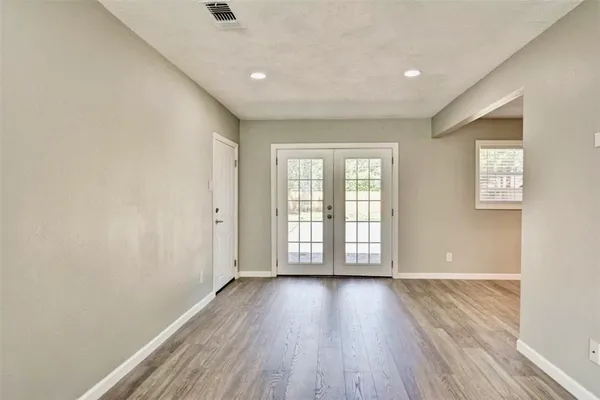 a view of an empty room with a window and wooden floor