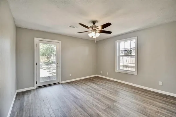 a view of a kitchen and an empty room with wooden floor and a window