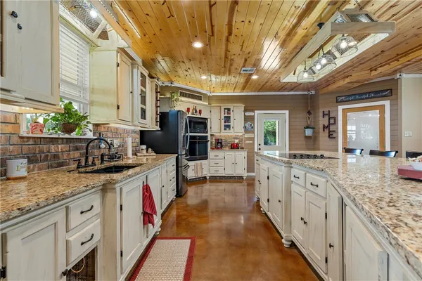 a large white kitchen with stainless steel appliances granite countertop a sink and cabinets