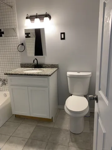a bathroom with a granite countertop sink a toilet and mirror