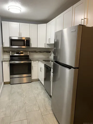 a kitchen with granite countertop a refrigerator and a stove top oven