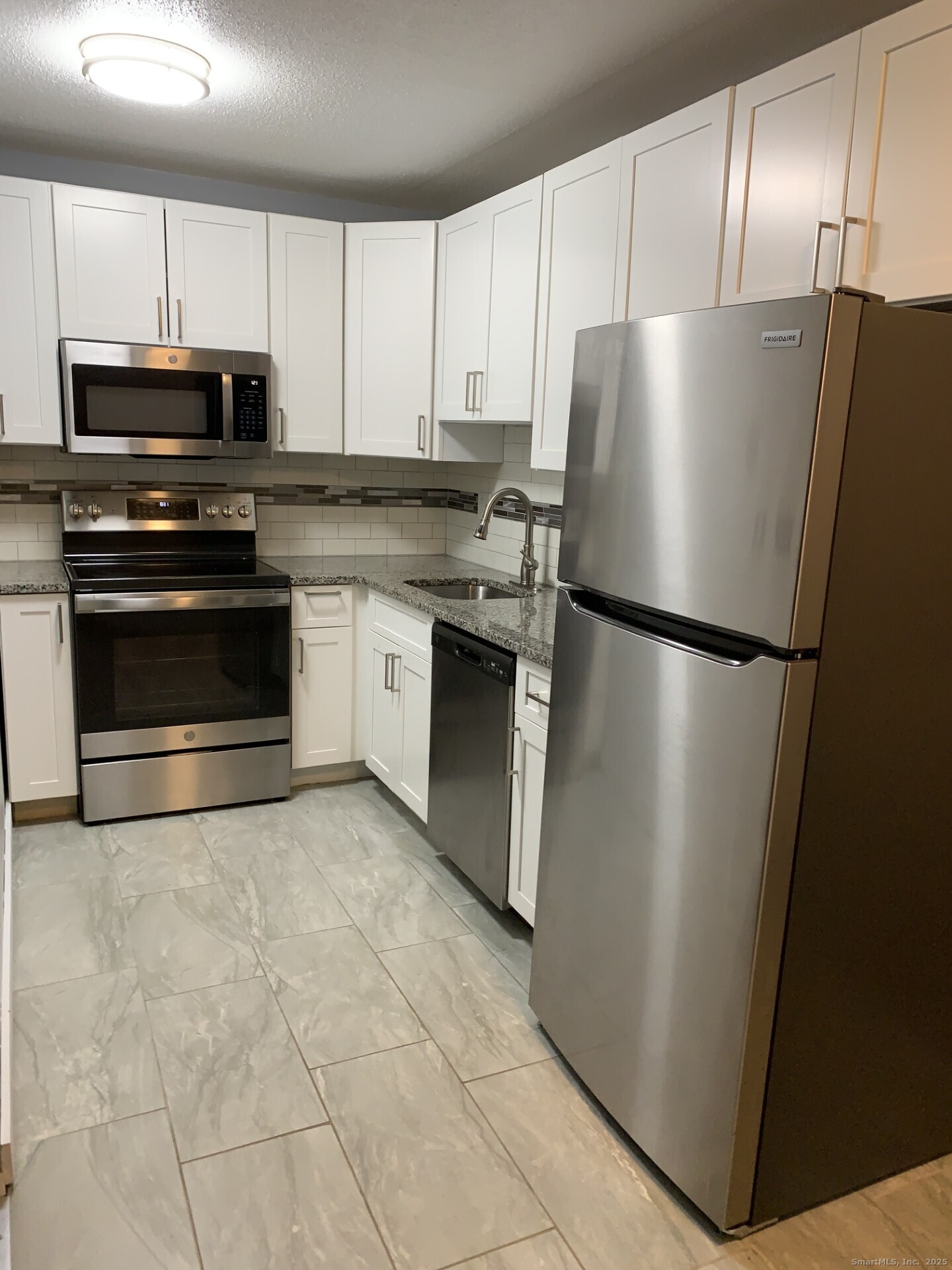 507 Emmett Street, Unit 13 Bristol, CT 06010 - Photo 7 of 16 a kitchen with stainless steel appliances granite countertop a refrigerator a microwave a sink and cabinets