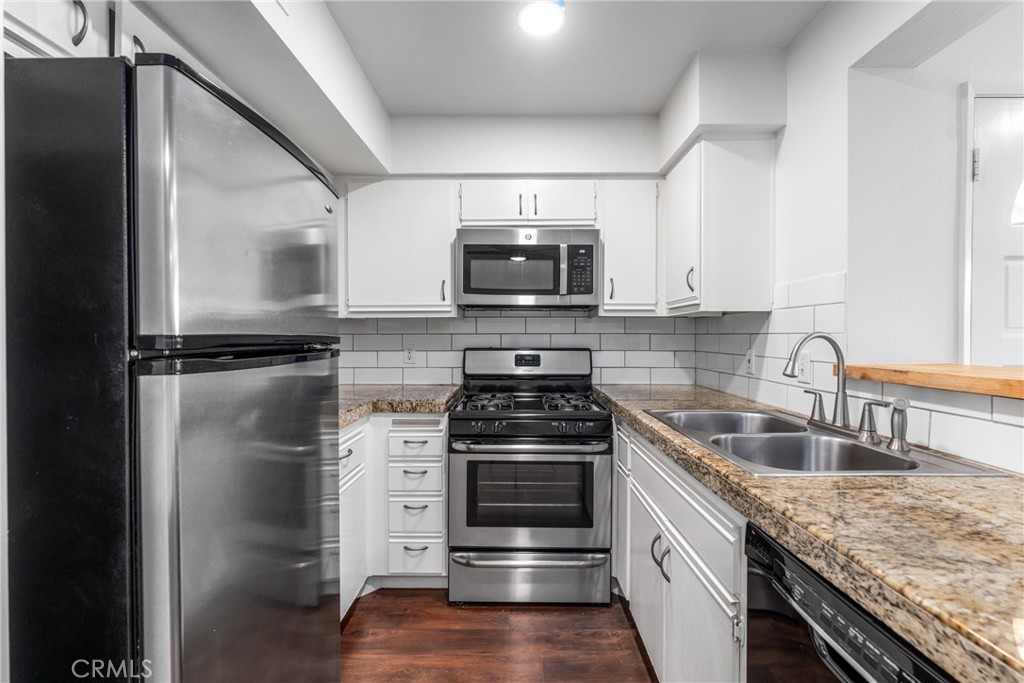 a kitchen with granite countertop a stove sink and refrigerator