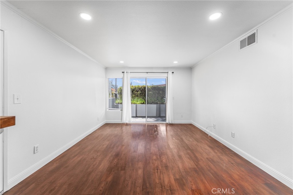 34264 Camino Capistrano, Unit 102 Dana Point, CA 92624 - Photo 5 of 37 an empty room with wooden floor and windows