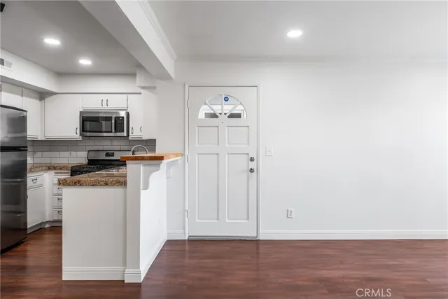 a kitchen with granite countertop a refrigerator and a stove top oven