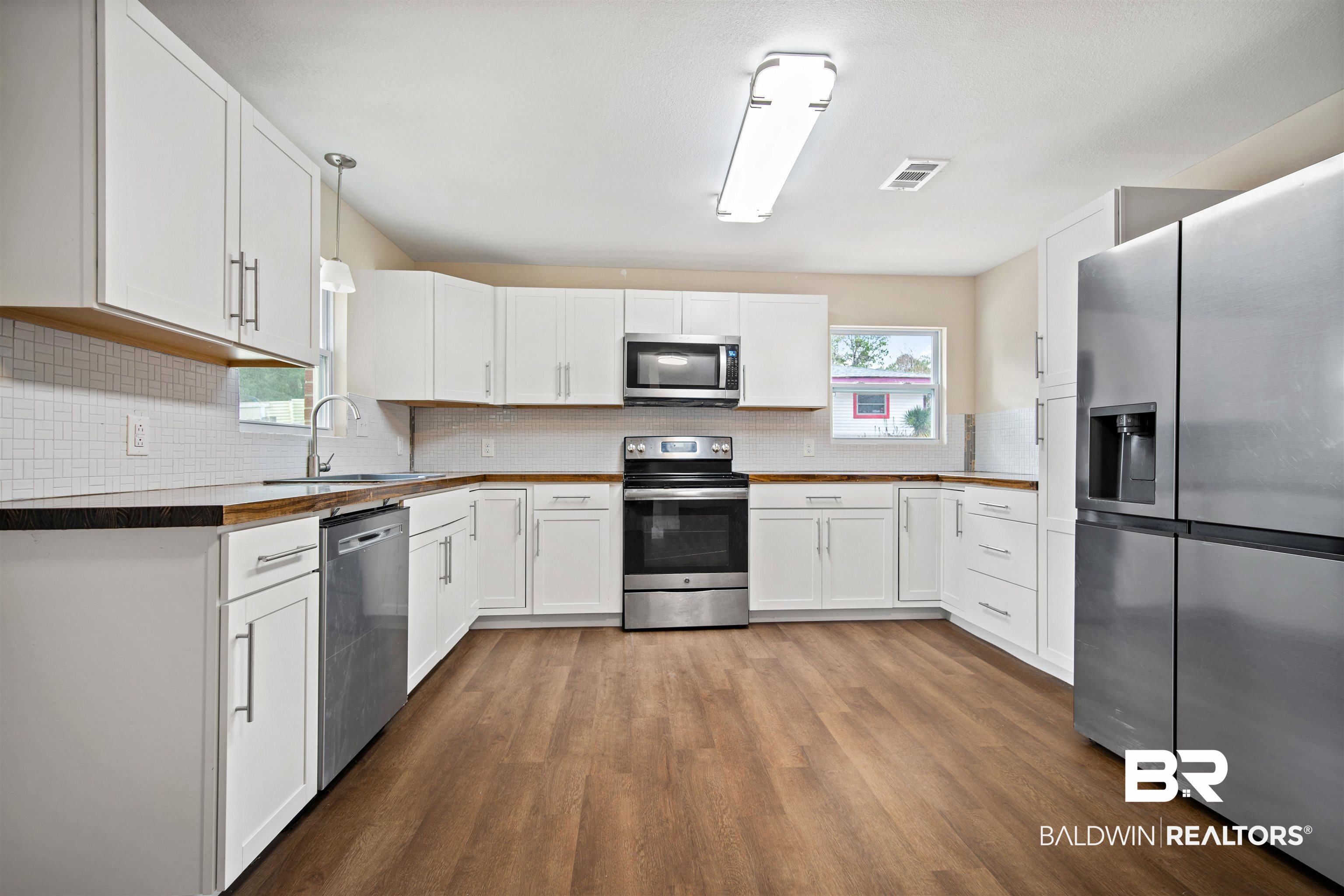 2119 Autrey Avenue Eight Mile, AL 36613 - Photo 7 of 22 Kitchen featuring appliances with stainless steel finishes, decorative light fixtures, white cabinetry, sink, and decorative backsplash
