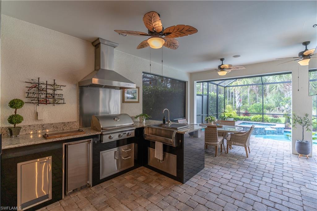 6848 Winding Cypress Drive Naples, FL 34114 - Photo 11 of 47 a kitchen with a stove a sink a oven and wooden cabinets