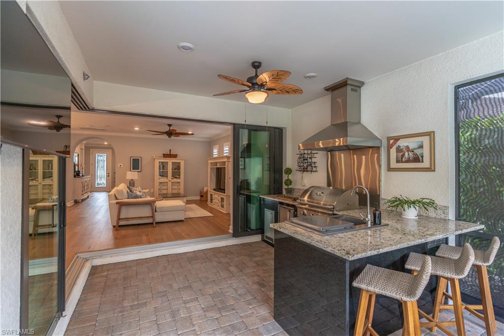 6848 Winding Cypress Drive Naples, FL 34114 - Photo 12 of 47 a dining room with wooden floor a chandelier a wooden table and chairs