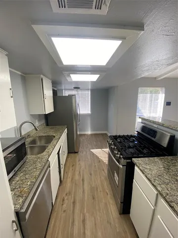 a kitchen with granite countertop a sink stove and cabinets