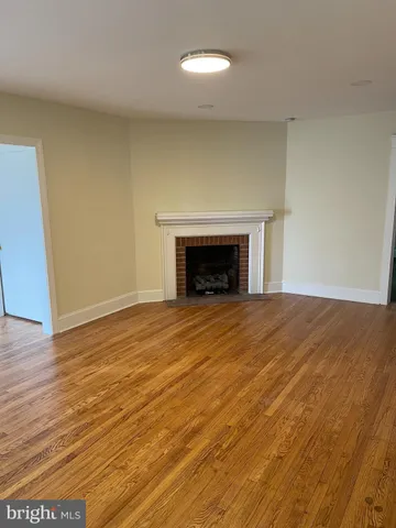 an empty room with wooden floor and a fireplace