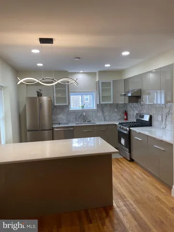 a large kitchen with kitchen island a sink dishwasher a stove and a refrigerator with wooden floor