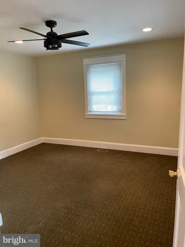 an empty room with a ceiling fan and window