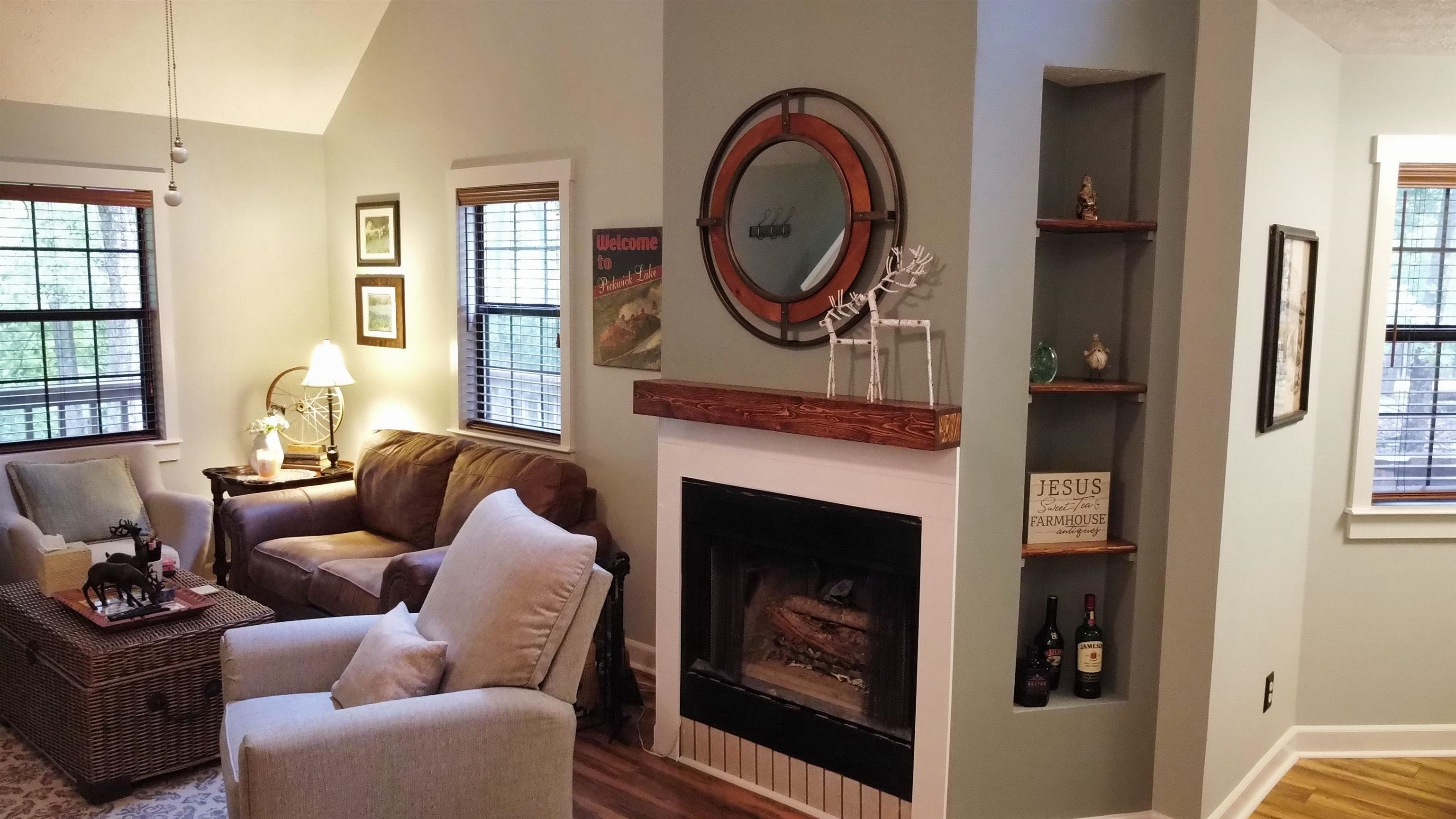 275 Bryson Harbor Road Counce, TN 38326 - Photo 19 of 23 Vaulted ceiling living area featuring a fireplace with a wood mantel, built-in shelving, wood-finish flooring, and multiple windows with wood blinds