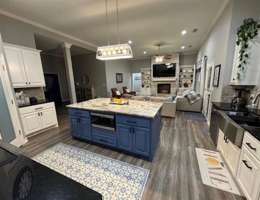 306 Embraer Road Abilene, TX 79602 - Photo 5 of 19 a large kitchen with stainless steel appliances kitchen island granite countertop a large stove a sink dishwasher and white cabinets with wooden floor