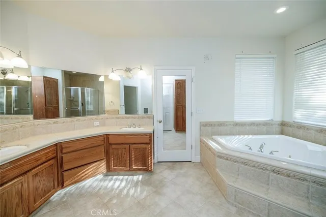 a bathroom with a bathtub a double vanity sink and mirror