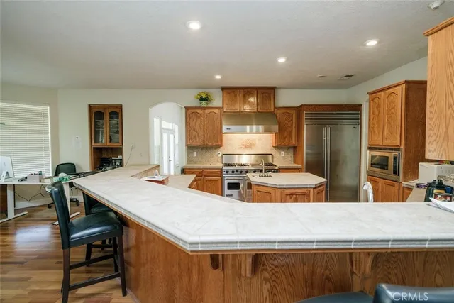 a kitchen with kitchen island a counter top space a sink stainless steel appliances and cabinets