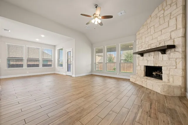 a view of an empty room with wooden floor fireplace and a window