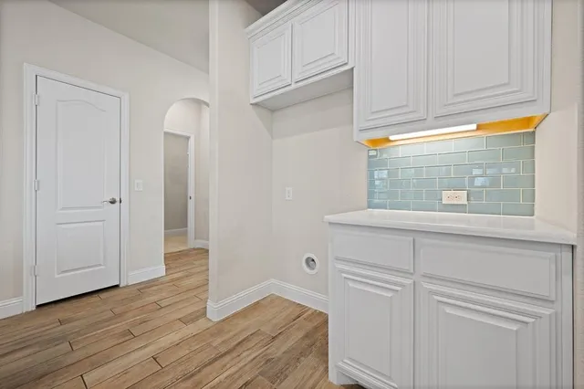 a large white kitchen with a refrigerator a sink dishwasher a stove and white cabinets with wooden floor