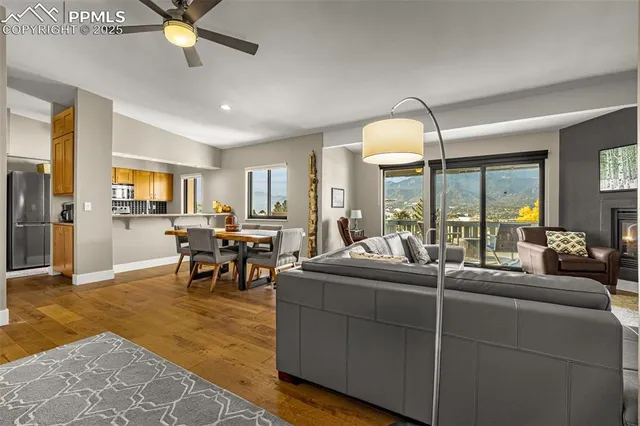 a living room with couches a dining table and chandelier with kitchen view