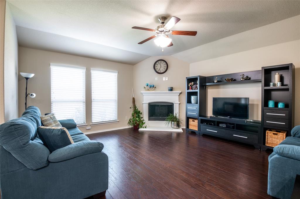 504 Rocky Pine Road McKinney, TX 75072 - Photo 13 of 36 Living area featuring ceiling fan, dark wood-type flooring, vaulted ceiling, and a fireplace with raised hearth
