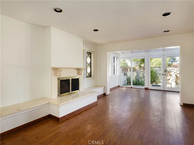 a view of a livingroom with furniture a fireplace wooden floor and windows