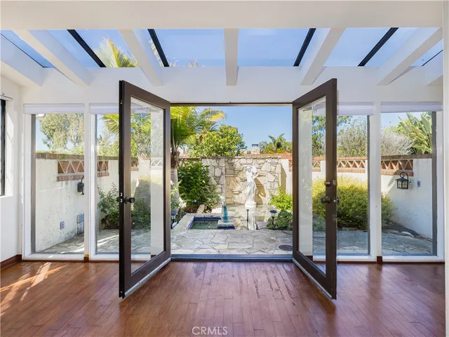 a view of a living room and balcony with wooden floor and glass windows
