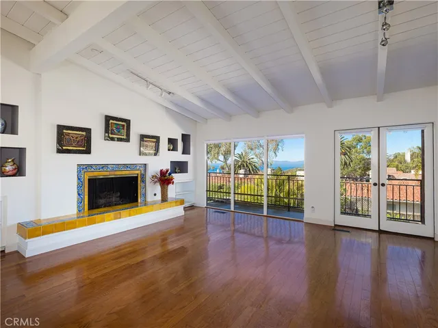 a view of an empty room with wooden floor and a fireplace