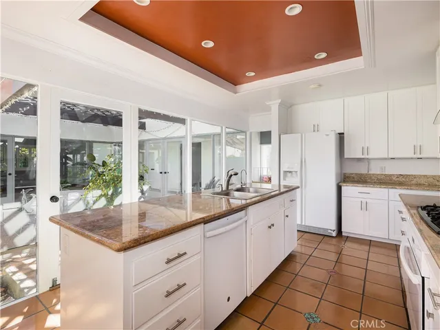a kitchen with granite countertop a sink and white cabinets