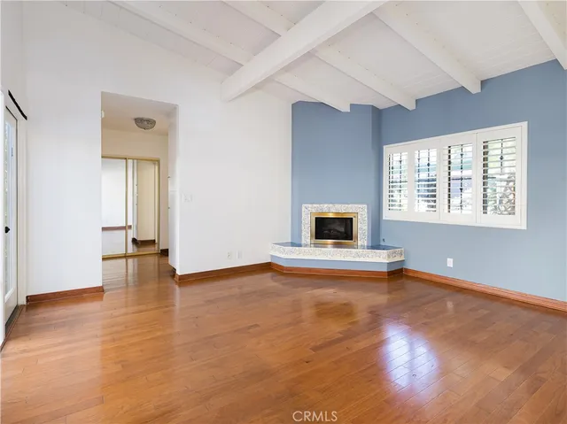 a view of an empty room with window and wooden floor