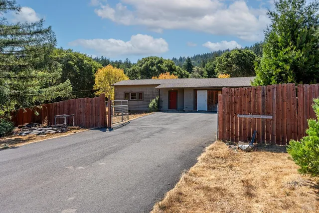 a view of a house with a small yard and wooden fence